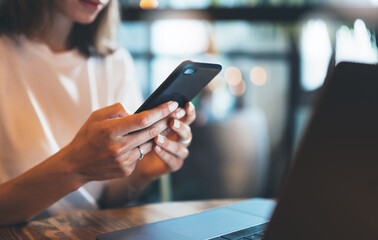 female hands holding smartphone using laptop office, hipster girl freelancer writing on mobile...