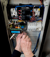 The man is repairing the switchboard voltage with automatic switches.