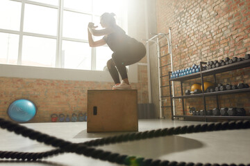 Delivering good health. Sportive woman using plyo box while having workout at industrial gym
