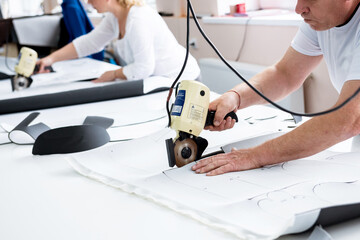 Male worker uses electric cutting fabric machine. Fabric industry production 