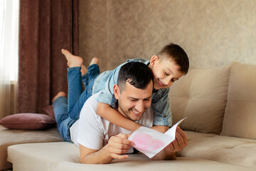 Happy family, father and son are lying on the couch.