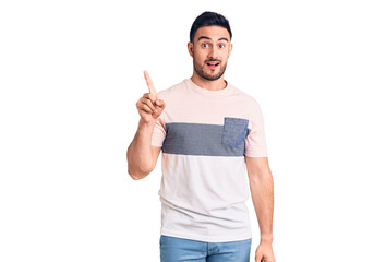 Young handsome man wearing casual clothes showing and pointing up with finger number one while smiling confident and happy.