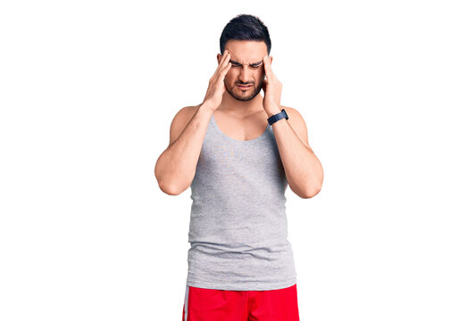 Young handsome man wearing swimwear and sleeveless t-shirt with hand on head, headache because stress. suffering migraine.