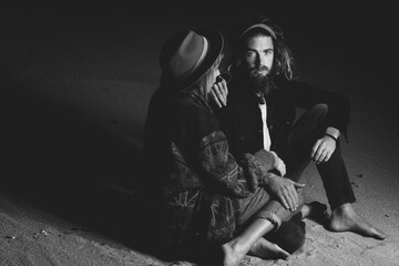 A beautiful trendy hippy couple in a beach sunset background