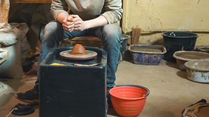 Professional potter working at kick wheel in home studio. Handmade mastery concept. Artisan at...