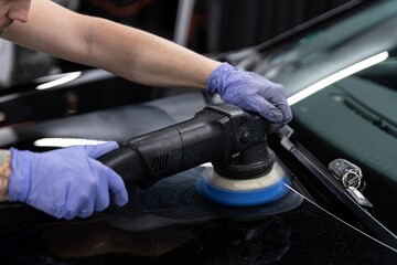 Fototapeta na wymiar Car detailing studio worker polishing car paint