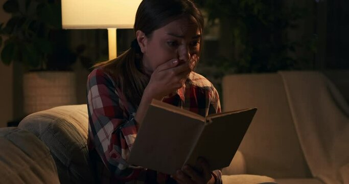 Woman feeling grateful after reading shocking content in book at night