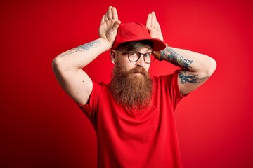 Young handsome delivery man wearing glasses and red cap over isolated background Doing bunny ears...