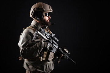 American special forces against a dark background, a soldier in military equipment holds weapons and looks at the copy space