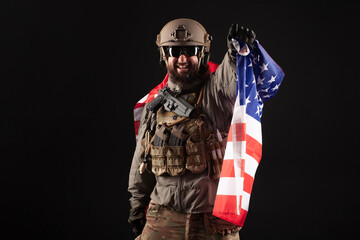 American commando in military equipment holds USA flag at night, modern ranger screams in the dark,...