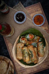 Vegan Eggrolls stuffed with bean thread noodles, carrot, peppers and mushrooms on traditional palm leaf plate and banana leaf