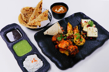 tandoori platter with chicken tikka, grilled prawns, and paneer along with dal makhani, wheat bread and chutneys, Indian food speciality