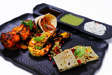 tandoori platter with chicken tikka, grilled prawns, and paneer along with dal makhani, wheat bread and chutneys, Indian food speciality
