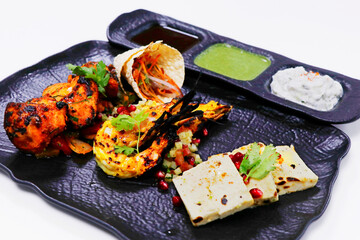 tandoori platter with chicken tikka, grilled prawns, and paneer along with dal makhani, wheat bread and chutneys, Indian food speciality