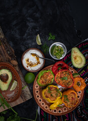 Vegetarian rice stuffed peppers along with side dishes in a traditional Mexican setting