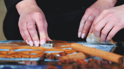 Slow motion of woman's hands using cookie cutter to make cookies. In front there are different spices.
