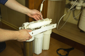 The master replaces dirty filters in the home water purification system. Human hands, filter,...