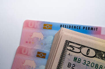 UK Biometric Residence permit cards and stack of 50 dollar banknotes. BRP cards released for Tier 2...