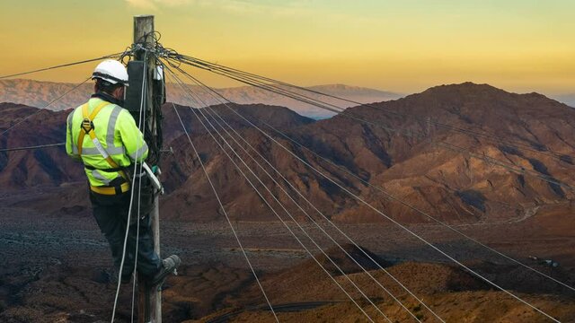 Lineman (Or Lineworker or Engineer) In A Remote Desert Landscape Fixing A Telephone Line