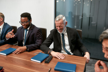 Funny joke. Happy business people in classic wear laughing while working together in the modern office