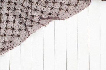 Vintage Lace or Netting that is black and brown and covering the corner of white boards background.  Horizontal that can be vertical.