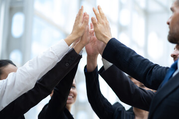 Happy successful multiracial business team giving a high fives gesture as they laugh and cheer...