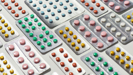 Composition with many medical pills, tablets pack in blister lying diagonally over white background. Health care, vitamins and treatment concept