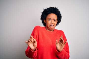 Young beautiful African American afro woman with curly hair wearing red casual sweater disgusted...