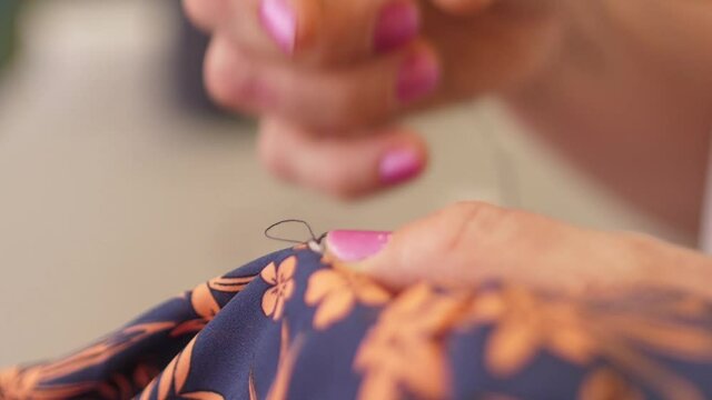 seamstress closeup woman hands sewing with needle and thread slow motion	