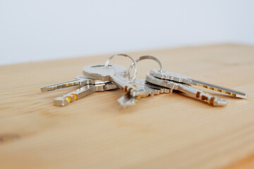 Bunch of keys on a shaped keychain at wooden table background. Concept for real estate or renting home with copy space,Close up.
