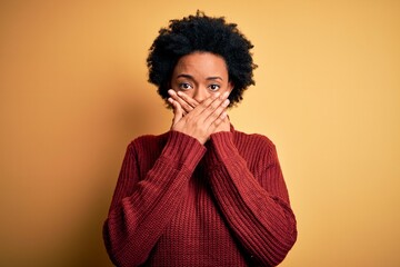 Young beautiful African American afro woman with curly hair wearing casual turtleneck sweater shocked covering mouth with hands for mistake. Secret concept.