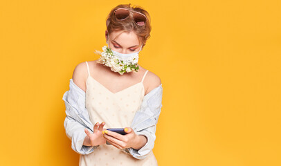 Beautiful woman in medical mask with flower design, holding telephone
