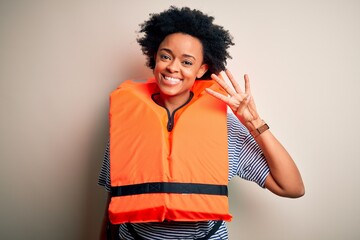 Young African American afro woman with curly hair wearing orange protection lifejacket showing and...