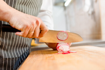 Radish on cutting board. Cut radish for ramen soup on kitchen . Chef cooks radish with knife in restaurant.