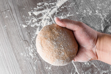 Wheat dough ball with flour in hands. Cooking pizza with italian white dough. Food blanks in restaurant.