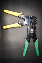 Yellow and green adjustable wire stripper joining head to head isolated on a black background, Adjustable wire stripper isolated isolated a black background, Wire stripper on black, crimping tool. 