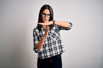 Young brunette woman with blue eyes wearing casual shirt and glasses over white background Doing...