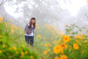 Fototapeta premium young woman in the field with flowers during fresh and foggy morning 