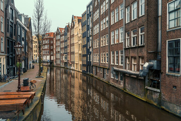 Naklejka premium Typical famous water canal and dancing houses in empty Amsterdam downtown, Netherlands.