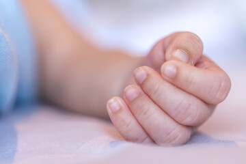 Close up image of cute small fingers of newborn baby while sleeping on the bed