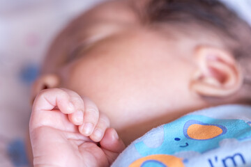 Small tiny hand and fingers of cute little newborn baby while sleeping on the bed at home