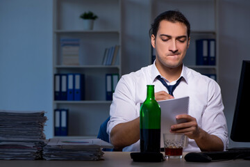 Alcohol addicted businessman working late in the office