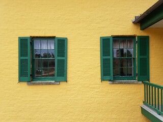 Fototapeta na wymiar yellow building with green shutters