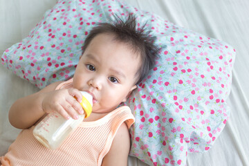 Cute little newborn baby boy drinking milk from milk bottle on the bed