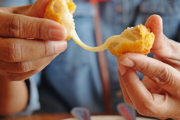 Woman's hand holding fried mozzarella cheese ball 