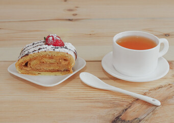 Sponge cake with tea on a wooden table.
One slice of biscuit roll and mug of black tea on a wooden table, closeup side view
