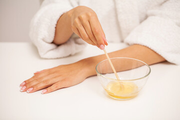 Fototapeta na wymiar Skin care, a woman applies wax to her hand to remove hair
