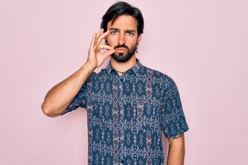Young handsome hispanic bohemian man wearing hippie style over pink background mouth and lips shut...