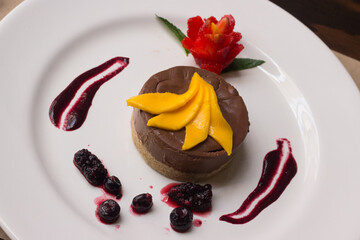Tarta de chocolate con trozos de mango y frutos rojos. 