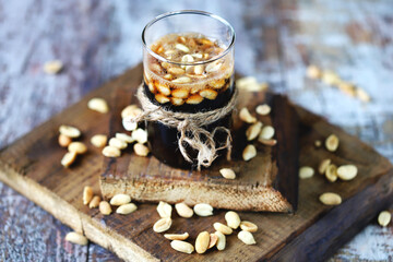 Selective focus. A glass of coca cola and peanuts. Salted peanuts in a glass with cola. American...